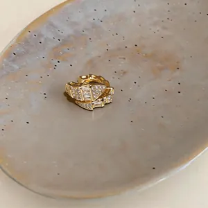 Vista dettagliata di un ear cuff dorato con zirconi e design geometrico