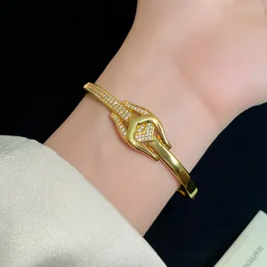 Nahaufnahme eines eleganten, mit 18 Karat vergoldeten Zirkonia-Knotenarmreifs am Handgelenk.