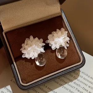Detailansicht weißer Harzblumenohrringe mit klaren Wassertropfenanhängern in Box