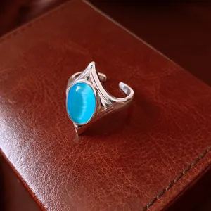 Close-up of vintage geometric open ring with vibrant blue cat's eye stone on leather texture