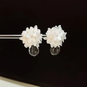 Makroansicht exquisiter weißer Blumenohrstecker aus Harz mit klarem Tropfenanhänger
