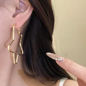Close-up view of a model wearing an 18k gold plated large star-shaped hoop earring detail