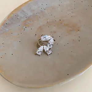 Elegante ear cuff in argento con zirconi a goccia posizionato su un piatto ceramico.