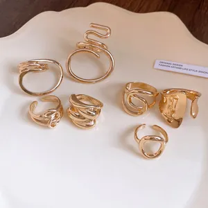 Close-up detail of various minimalist gold-plated geometric hollow rings on a plate
