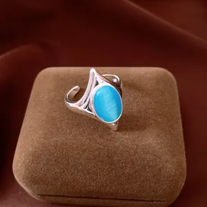 Detail of a vintage silver ring with an oval blue cat's eye stone on a brown box.