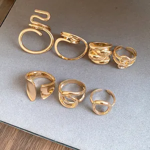 Close-up of diverse gold-tone hollow rings with intertwined and oval minimalist designs.