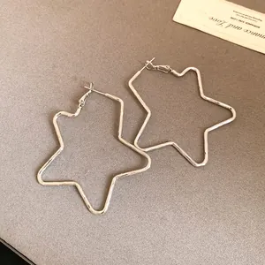 Close-up of oversized star-shaped silver-plated hoop earrings on a neutral background