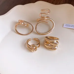 Macro detail of four gold-plated hollow rings featuring oval and cross-wound minimalist designs
