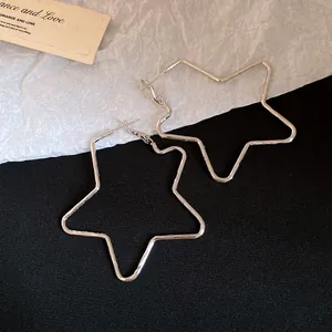 Detail shot of minimalist oversized silver star-shaped hoop earrings with polished finish