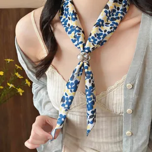 Detailed shot of a blue floral skinny scarf styled with a pearl resin buckle on a model