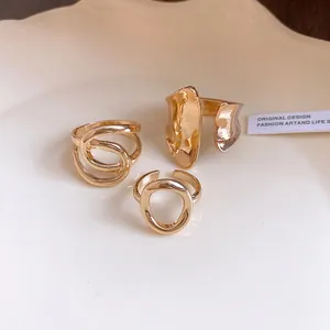 Close-up detail of minimalist gold hollow-out and cross-wrap rings with irregular textures
