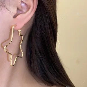 Detail view of large 18k gold plated silver needle star hoop earring worn on ear