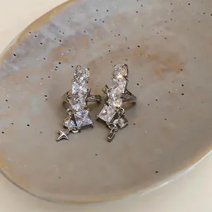 Primo piano di ear cuff a stella in argento con zirconi scintillanti su un piatto di ceramica.