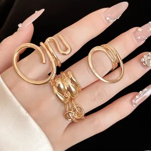 Detailed view of gold twisted hollow oval rings on a hand with luxury manicured nails