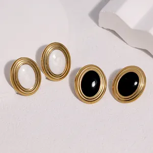 Dettaglio di orecchini vintage in acciaio dorato con inserti in smalto nero e bianco.