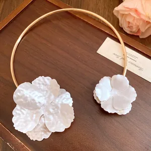 Detailed close-up showing the elegant metal collar necklace with textured white floral design