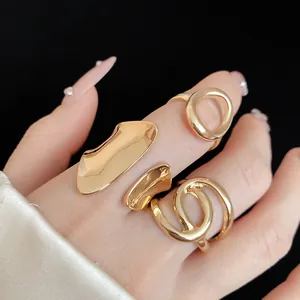 Detailed close-up showing gold irregular hollow wrap rings on finger with black backdrop