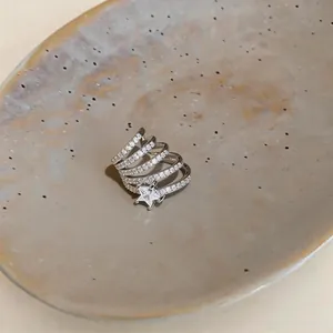Dettaglio macro di un orecchino a clip a stella con zirconi su un piatto di ceramica.