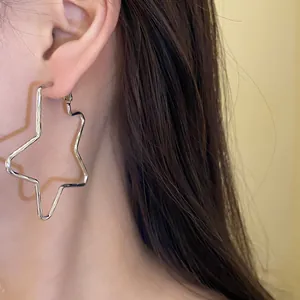 Close-up detail of a minimalist star-shaped silver hoop earring worn by a model