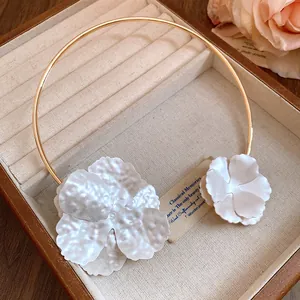 Close-up of elegant metal flower choker with hammered texture in white and gold.