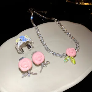 Detailed view of pink resin flower necklace and earring set with cubic zirconia