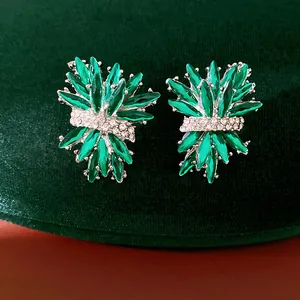 Detalle de pendientes de botón de fuegos artificiales con piedras verdes y cristales.