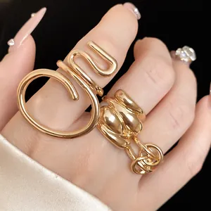 Close-up of chunky gold-toned oval crossed and winding hollow rings on fingers