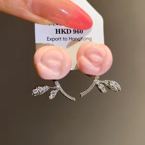 Close-up detail of elegant pink resin rose earrings with sparkling rhinestone stems
