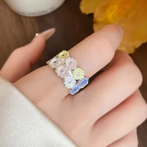 Detailed macro view of a stylish resin flower ring with sparkling crystals worn on a finger.