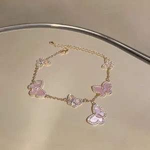 Nahaufnahme eines eleganten goldenen Schmetterlingsarmbands mit rosa Steinen und Zirkonia.