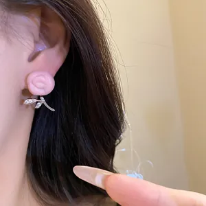 Detailed close-up of a pink resin flower earring with sparkling zircon leaves on ear