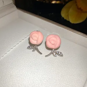 Close-up of elegant pink resin flower earrings with sparkling cubic zirconia stems