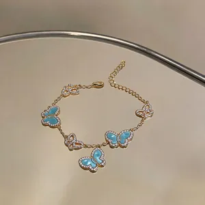 Detailansicht eines eleganten goldfarbenen Schmetterlingsarmbands mit blauer Emaille und Zirkonia