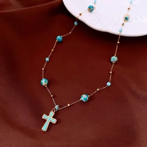 Elegante Vintage-Goldkette mit blauem Kreuzanhänger und marmorierten Perlen-Details