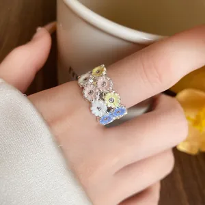 Close-up of a colorful enamel flower ring with sparkling zircons on a model's finger