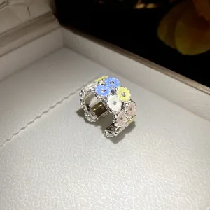 Macro shot of a silver band ring with colorful pastel resin flowers and zircon centers.