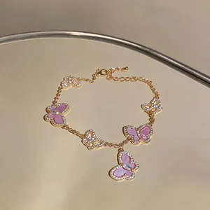 Detail eines rosa Schmetterlingsarmbands mit funkelnden Zirkonia auf einer goldfarbenen Kette.