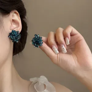 Close-up detail of blue beaded grape earrings with a transparent hydrangea floral design
