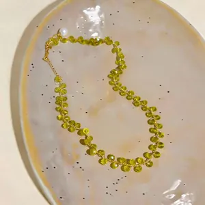 Close-up of 14k gold plated necklace with olive green faceted beads and pearl detail.
