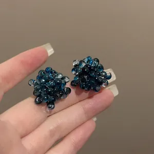 Detail shot of translucent blue grape cluster bead stud earrings with glass texture