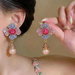Close-up of elegant flower-shaped drop earrings featuring pink crystals and pearl charms