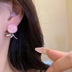 Detailed close-up of a pink resin flower earring with cubic zirconia leaves on ear