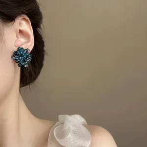 Detail view of translucent blue grape cluster beaded earrings worn by a model
