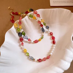 Close-up detail of a colorful beaded and pearl necklace inside a white shell tray