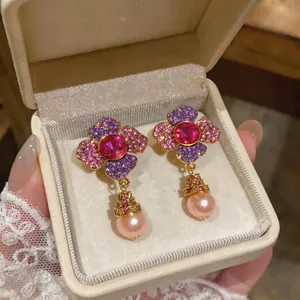 Close-up of exquisite floral earrings with micro-paved stones and peach pink pearls