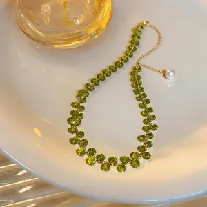 Close-up view of a green beaded necklace featuring a gold chain and a delicate pearl pendant.