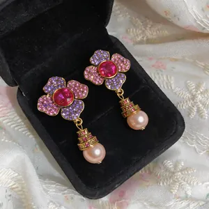 Detailed view of flower-shaped crystal earrings with elegant pink pearl drops in box