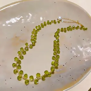 Detailed view of olive green beaded necklace with 14k gold plated chain and pearl