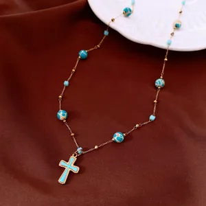 Nahaufnahme einer blauen Kreuzhalskette mit marmorierten Perlen auf braunem Seidenhintergrund.