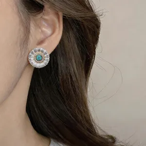 Close-up of a vintage flower stud earring with turquoise center and zircon details on ear